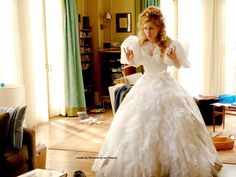 a woman in a white wedding dress standing in a living room