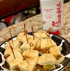 small sandwiches with toothpicks are on a plate next to a bottle of soda