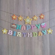 a happy birthday banner made out of plastic beads on a wooden surface with other decorations