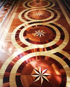 a wooden floor with several circles and stars on the center, inlaid to it