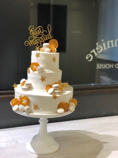 a three tiered white cake with gold stars on top