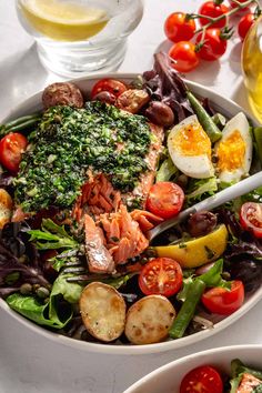 two bowls filled with different types of salads and vegetables on top of a table