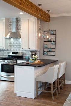 a kitchen with white cabinets and an island in the middle, surrounded by bar stools