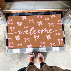 someone standing in front of a welcome mat with pink bows on it and the words welcome