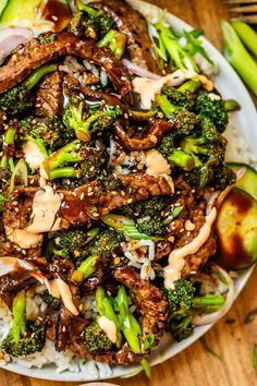 a white plate topped with meat and broccoli covered in sauce next to green beans