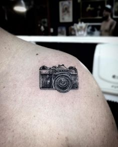 a camera tattoo on the back of a man's shoulder