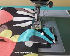 the sewing machine is on top of the colorful fabric that has been sewn together