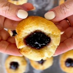 two hands holding a doughnut with jelly on it