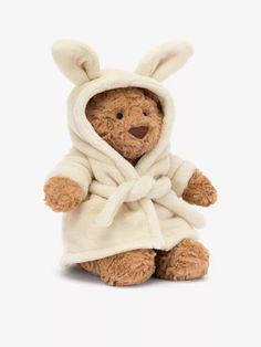 a brown teddy bear wearing a white robe and bunny ears on it's head