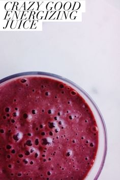 a glass filled with red liquid sitting on top of a table next to a banana