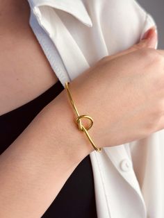 Elevate your wrist with our exquisite gold heart bangle, a symbol of timeless elegance and heartfelt sentiment. Crafted from lustrous gold-plated stainless steel, this bangle boasts durability and a luxurious shine that radiates sophistication.  The delicate heart charm adds a touch of romance, making it a perfect gift to express love and appreciation. Whether worn alone as a statement piece or stacked with other favorites, this bangle effortlessly transitions from day to night, enhancing any ensemble with its understated beauty.  Treat yourself or someone special to this versatile and enduring piece of jewelry, sure to become a cherished addition to any collection. Gift Bangle Heart Bracelet With Jubilee Detail, Valentine's Day Dainty Bangle Bracelets, Adjustable Gold Open Heart Jewelry, Adjustable Open Heart Gold Jewelry, Minimalist Bangle Jewelry For Valentine's Day, Minimalist Gold Bangle Heart Bracelet, Gold Minimalist Heart Bangle Bracelet, Elegant Gold Heart-shaped Bangle, Minimalist Adjustable Heart Bangle Bracelet