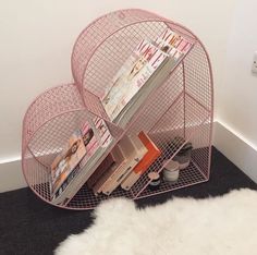 a magazine rack with magazines on it in a corner next to a white cow skin rug