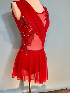 a red dress with sequins on the back is displayed in front of a mannequin