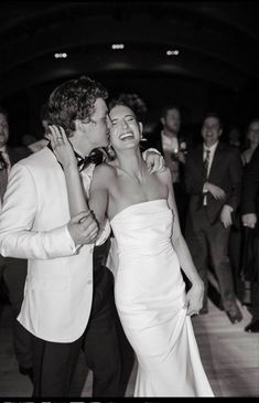 a man and woman are kissing on the dance floor at their wedding reception in black and white