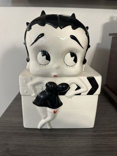 a white and black figurine sitting on top of a refrigerator with eyes wide open