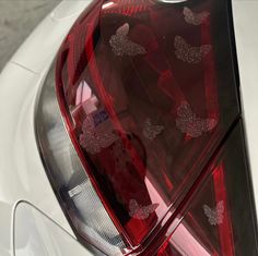 the tail light of a white car with butterflies on it