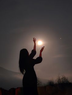 a woman reaching up to catch a frisbee in the air with her hands