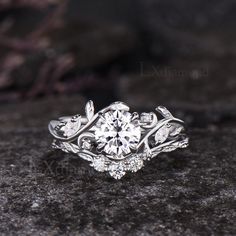 a close up view of a diamond ring with leaves on the band and center stone