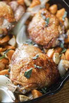 a pan filled with chicken and vegetables on top of a wooden table