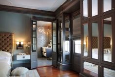 a bedroom with wooden floors and mirrored doors leading to the other rooms in the house