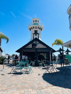 people are sitting at tables in front of a building with a clock tower on top