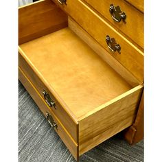 an empty drawer is open on the carpeted floor in front of a wooden dresser