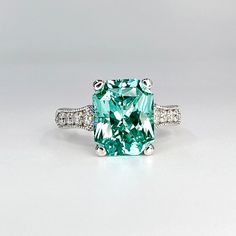 an emerald colored ring with diamonds on the sides