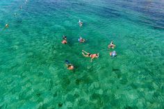 people are swimming in the clear blue water