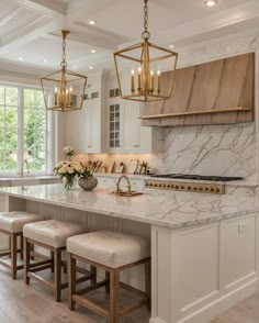 a large kitchen with marble counter tops and gold accents on the island, along with two stools