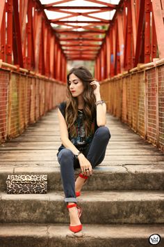 a woman sitting on some steps with her hand in her hair and wearing red shoes