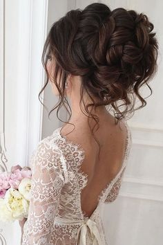 the back of a woman's head with flowers in her hair, holding a bouquet