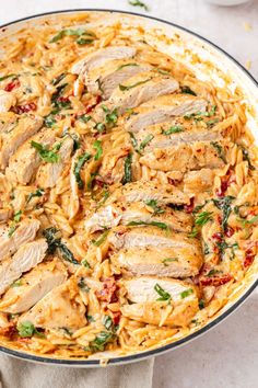 chicken and spinach pasta in a pan on a white counter top with a napkin