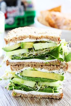 a sandwich cut in half sitting on top of a cutting board next to cucumbers