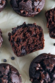 several chocolate muffins sitting on top of a piece of parchment paper next to each other