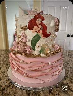 a little mermaid cake with pink icing and gold decorations