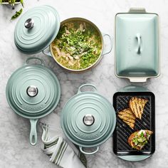 various pots and pans with food in them on a marble counter top next to utensils