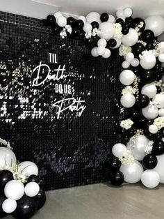 black and white balloons are hanging from the wall in front of a party backdrop that says,