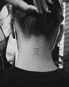 a woman's neck tattoo with the letter t on her left side behind her ear