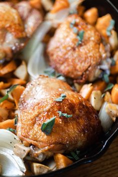 a pan filled with chicken and vegetables on top of a wooden table