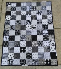 a black and white patchwork quilt on the ground