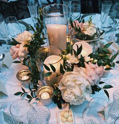 a centerpiece with candles and flowers is displayed on a table set for an event