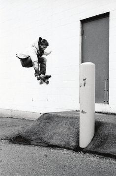 a man flying through the air while riding a skateboard next to a white wall