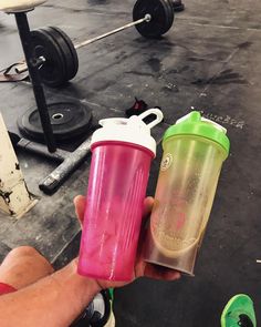 a person holding two different colored shakers in their hands, one is pink and the other is green