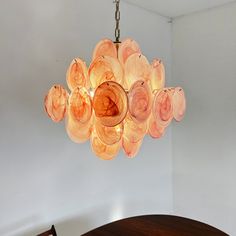 a chandelier hanging from the ceiling in a room with white walls and wooden table