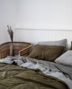 an unmade bed with two wicker baskets on the headboard and green sheets