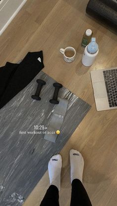 a person sitting on the floor with their feet up next to a yoga mat and laptop