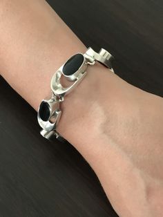 Vintage Taxco Mexico Modernist Sterling Silver Black Onyx Oval Sculptural Link Bracelet.  Silver Bracelet. Heavy bracelet weighing in at 56.88 grams. Hand polished cleaned ready to wear.  Markings: 925, Mexico TA-79 Size: 6 1/2 Total inside circumference so wrist up to that size, Links are 1" long x 5/8 wide.  Weight: 56.88 grams Condition: Vintage pre-owned. NO defects reflecting standard wear. Closure works as designed. Hand polished cleaned ready to wear.  See more of our jewelry- www.etsy.com/shop/ModManDesign Modern Black Oval Link Jewelry, Black Polished Finish Bracelet For Formal Occasions, Modern Black Sterling Silver Bracelet For Formal Occasions, Formal Black Enamel Metal Bracelets, Modern Black Enamel Bracelets For Formal Occasions, Modern Black Enamel Bracelet Jewelry, Modern Black Enamel Jewelry Bracelet, Modern Black Enamel Bracelet, Elegant Black Oval Bracelets