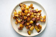 a white plate topped with cooked potatoes on top of a table