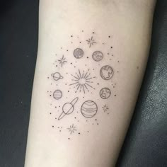 a small tattoo on the arm of a woman with planets and stars around it in black ink