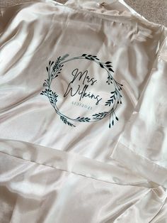 The perfect bridal shower, engagement party, wedding or anniversary gift! These personalized bridal robes display your new Mrs. name within a beautifully decorated wreath that is permanently printed on high quality comfortable silk. This satin robe feels so luxurious and flatters all shapes and sizes...a true classic robe to enjoy for years to come! Each robe comes with an interior tie to tighten or loosen the robe as well as a removable sash belt.  Your wedding is a monumental day that should be cherished and remembered; with these robes I hope to be able to provide something that can enhance the special memories of your big day.  DESIGN Includes:  -Beautifully decorated wreath -Your New Last Name  -Date of Wedding  Adding/Changing Design: (No Additional Charges) -Add words such as 'BRIDE Unique Bride Gifts, Personalized Bride Robe, Robe For Bride, Wedding Day Robes, Bridal Robes Personalized, Satin Bridal Robe, Bridal Party Robes, Unique Bride, Bridal Robe